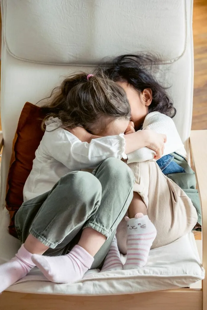Two girls embracing on a chair, finding comfort after hearing creepy true stories.