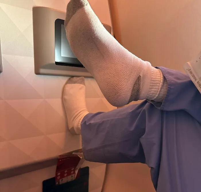 Rude passenger with socks on putting feet up on the screen, illustrating a plane seatmate from hell