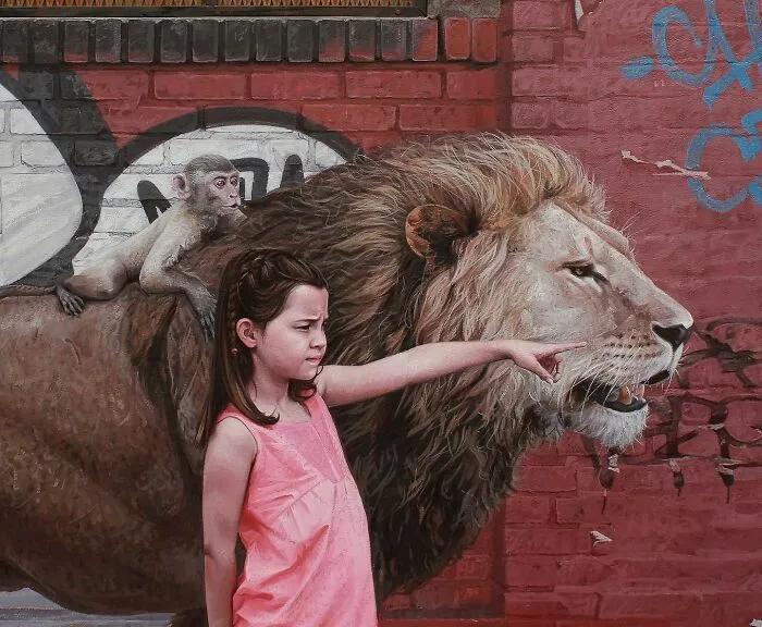 Dystopian painting by Kevin Peterson showing a young girl, a monkey, and a lion by a brick wall with graffiti