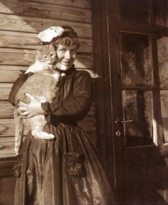A smiling Victorian woman holds a large fluffy cat in a charming vintage cat photo.