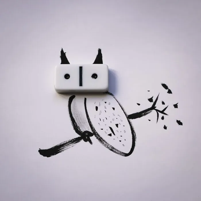 A playful illustration of an owl sitting on a branch, with a white domino used as its eyes
