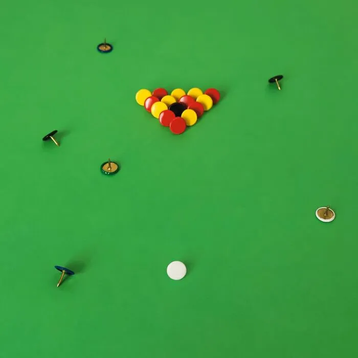 Playful illustrations of colorful pushpins arranged like a game of pool on a green surface