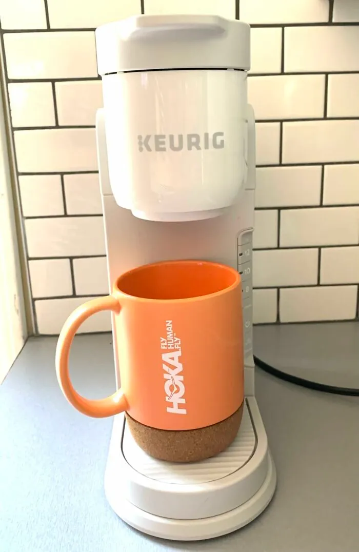An orange Hoka mug sits under a white Keurig coffee maker, a Prime Big Deal Days favorite