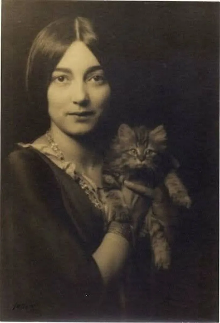 Vintage cat photo of a young woman with a classic middle part holding a fluffy kitten