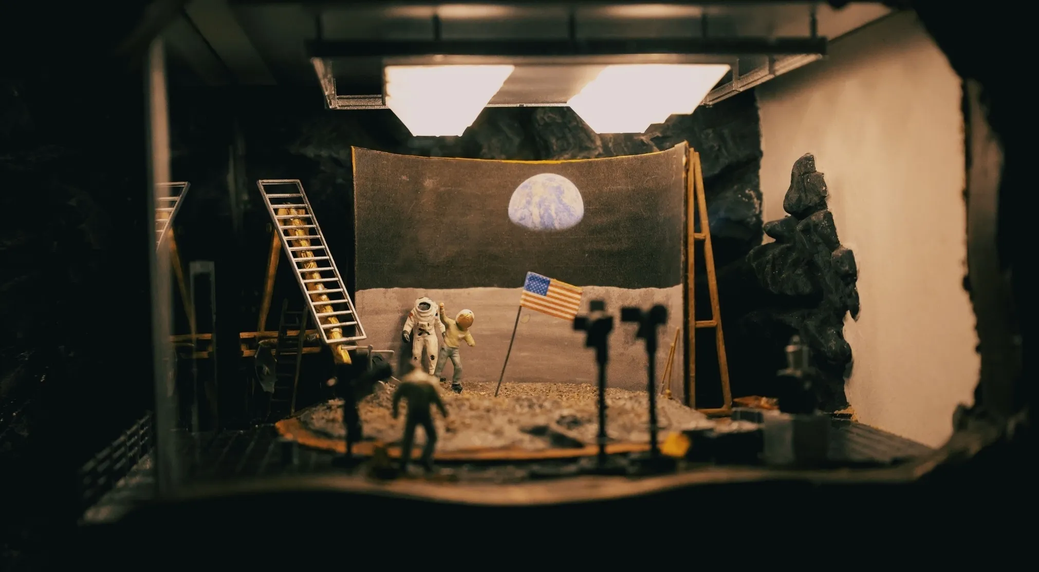 Miniature diorama simulating a Moon landing, questioning UFO and conspiracy theories with astronauts and an American flag.