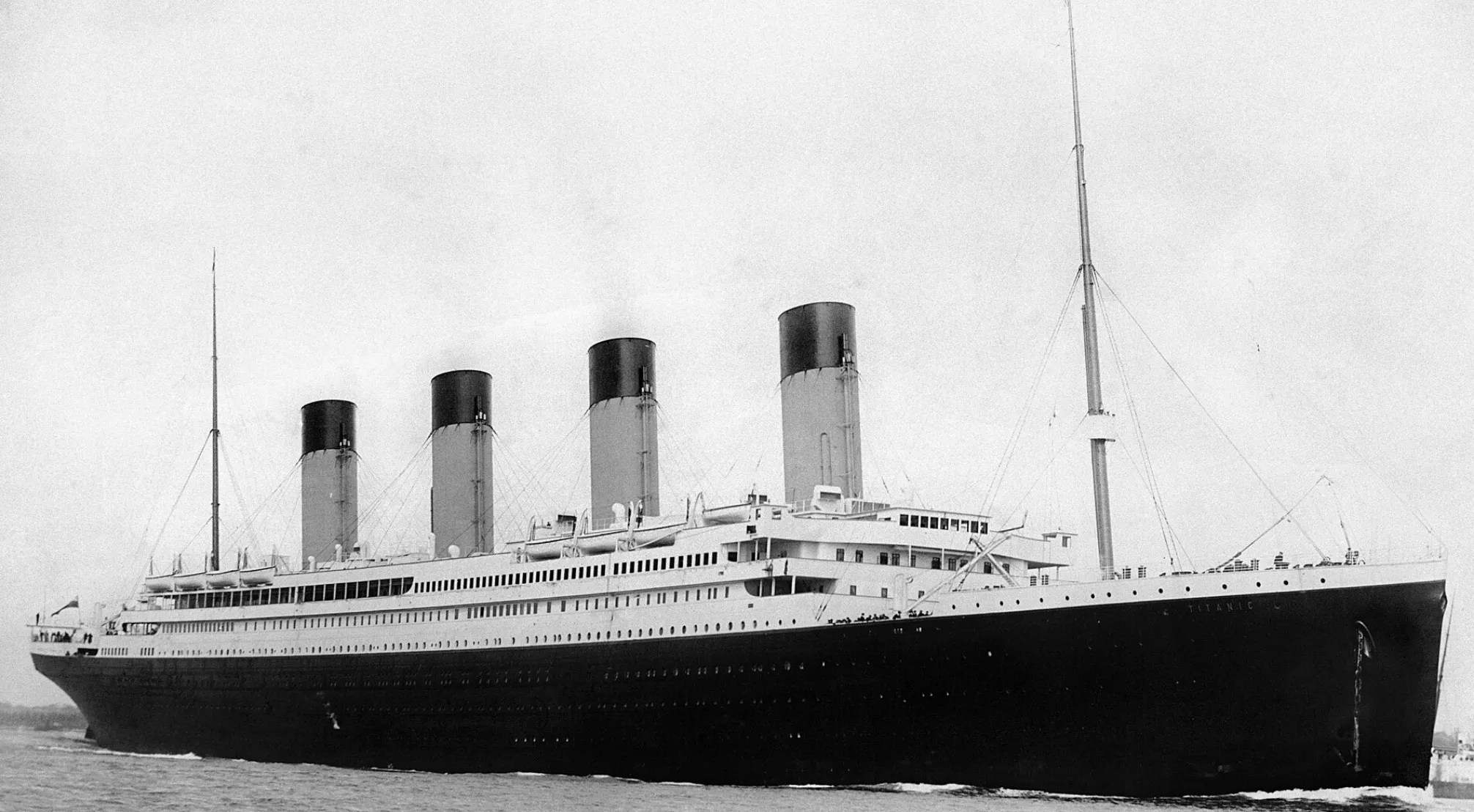 A black and white image of the full Titanic ship sailing on calm waters, relating to UFO and Conspiracy Theories Trivia.
