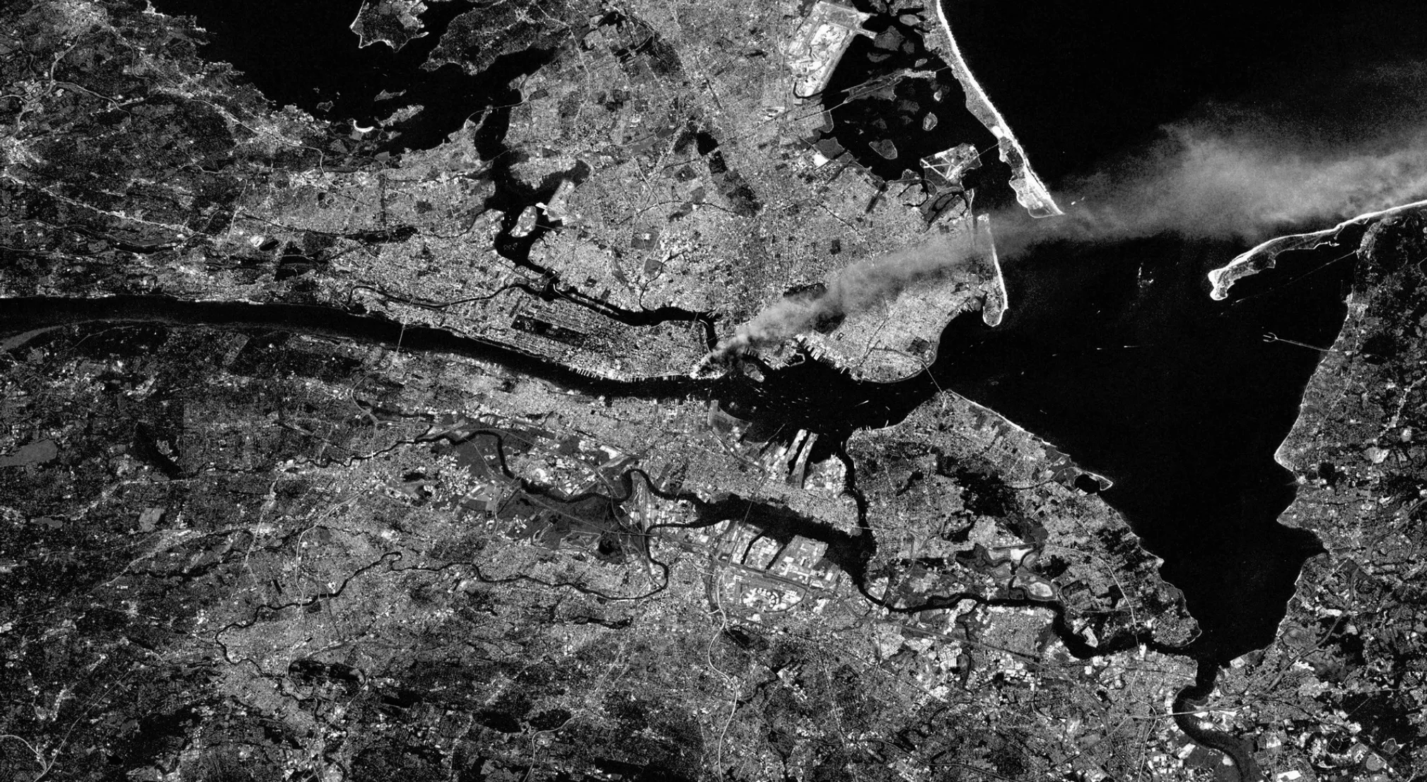Satellite view of a city with smoke rising over Manhattan, relevant to 9/11 conspiracy theories.