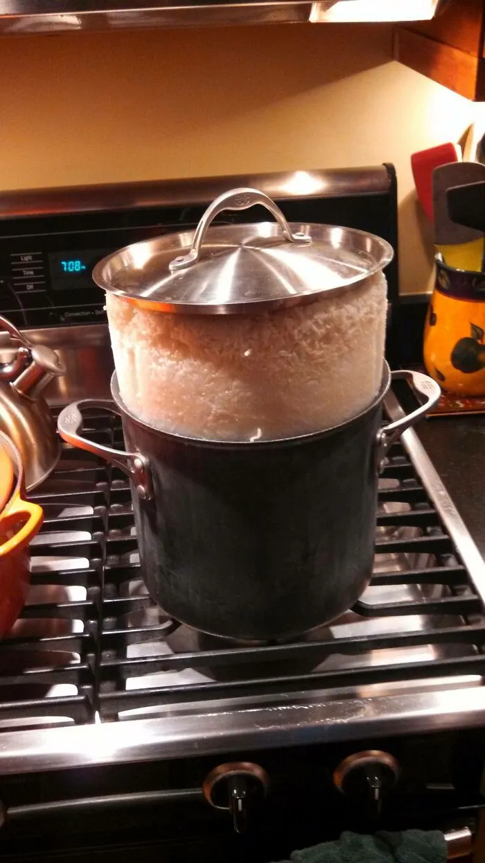 An overflowing pot of rice on a stovetop, demonstrating a humorous kitchen fail.