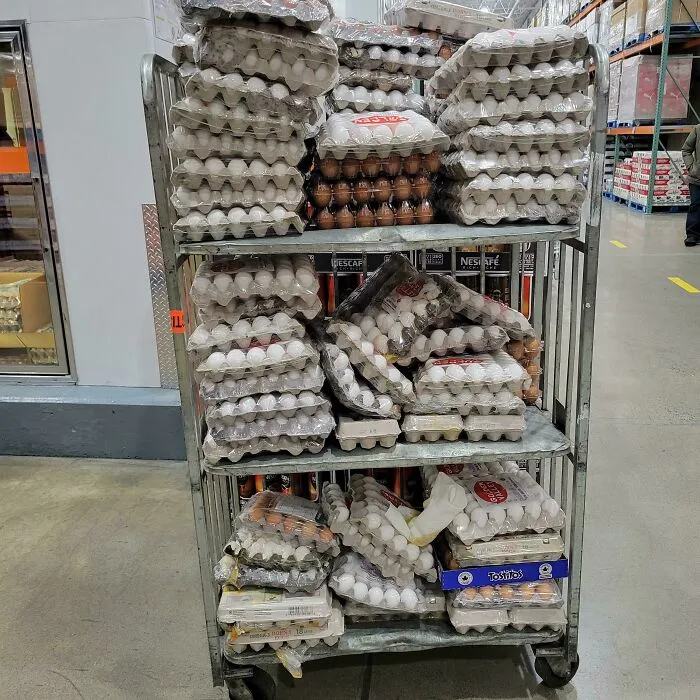 A rolling cart stacked high with numerous egg cartons, indicating a massive kitchen fail if dropped.