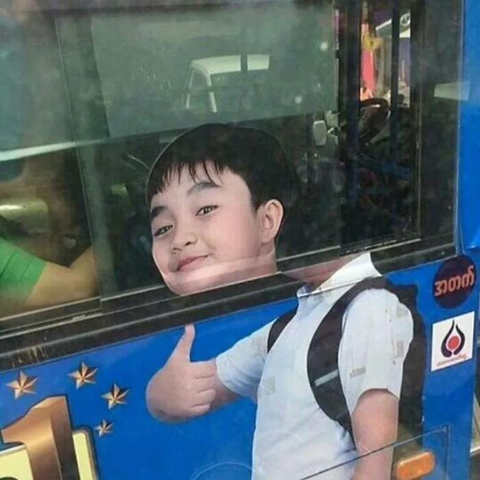 A hilariously placed ad for a child with a backpack giving a thumbs-up, appearing to stick their head out a bus window, proving context matters.