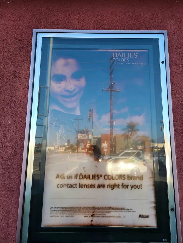 There's An Optometrist Business Near My House That Has This Giant Poster Outside Advertising Colored Contacts. It Seems To Have Aged In A "Is That A Demon?" Way