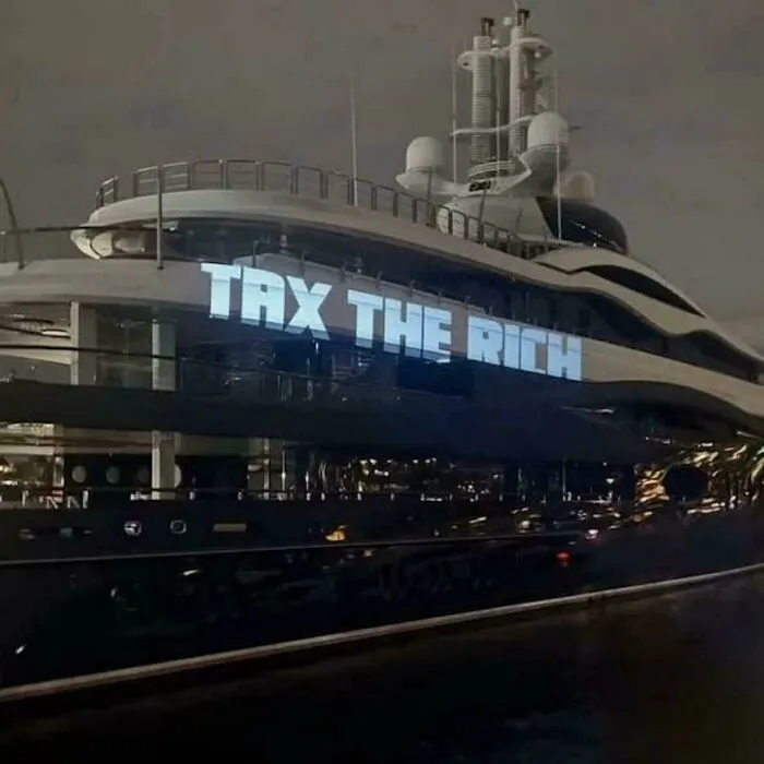 Local Artist Light Guerrilla Projected “Tax The Rich” On The Side Of Mark Zuckerberg’s Boat While It Was Docked At Seattle’s Lake Union