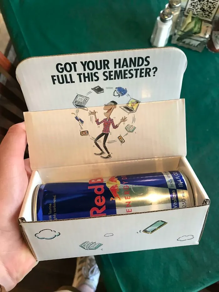 An open box containing two Red Bull cans, promoting energy for a horrid and sad world.