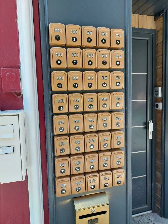 A wall with 39 small lockboxes and a larger mailbox below, depicting a horrid world.