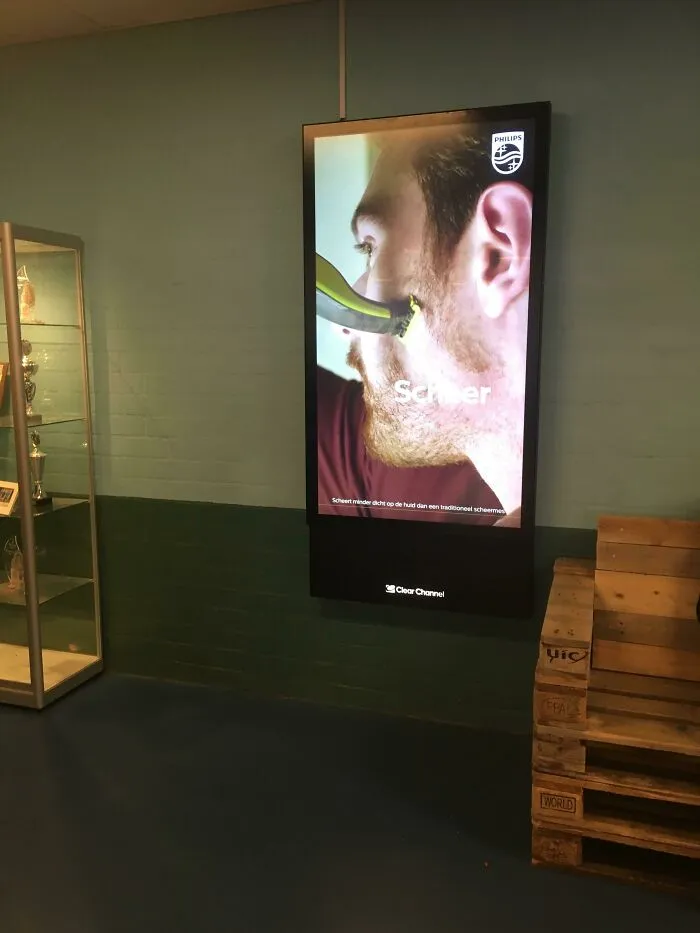 A digital display on a teal wall showing an advertisement for Philips shaver, highlighting a horrid world problem.