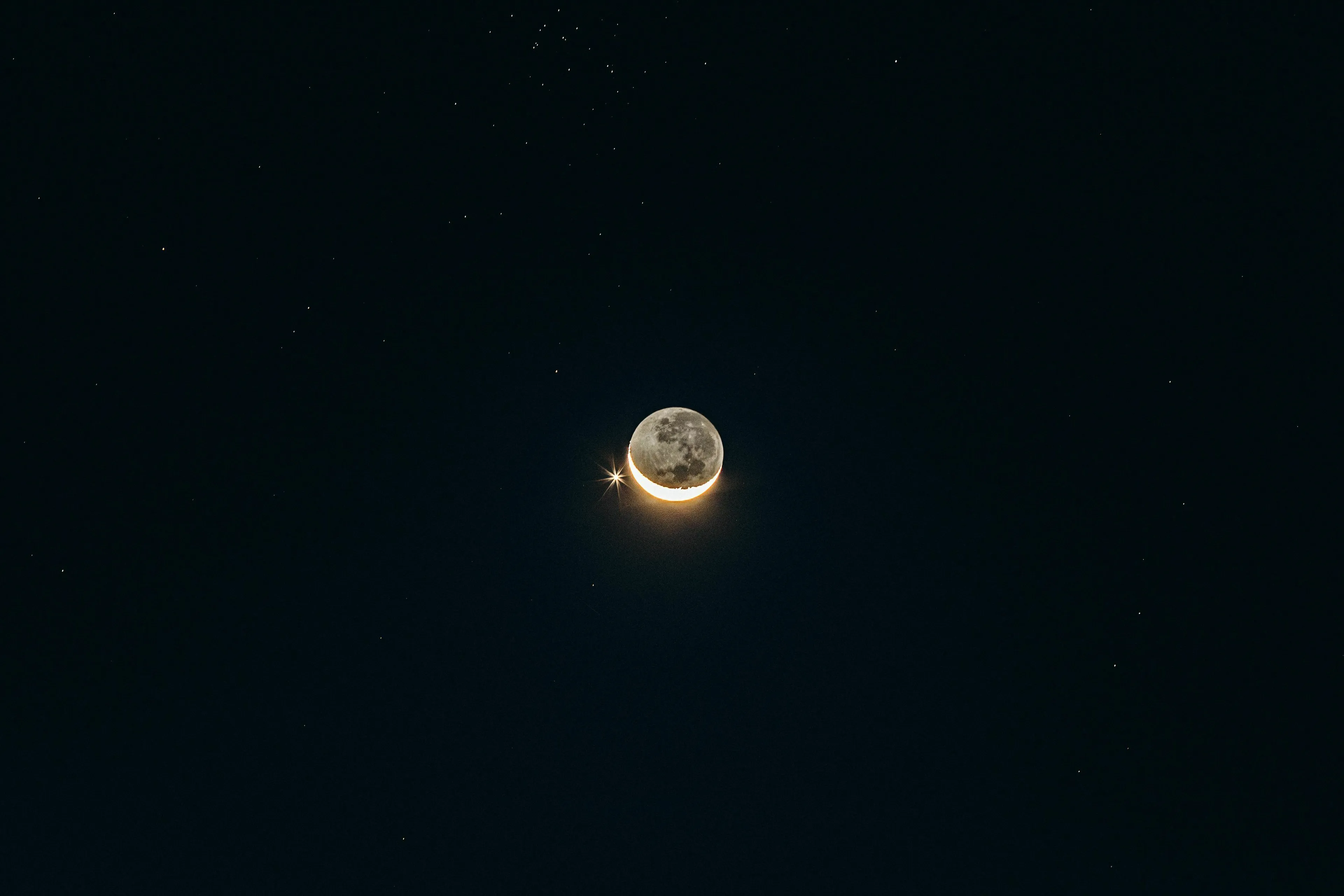 A crescent moon with a bright star nearby against a dark night sky, symbolizing the vastness of space.