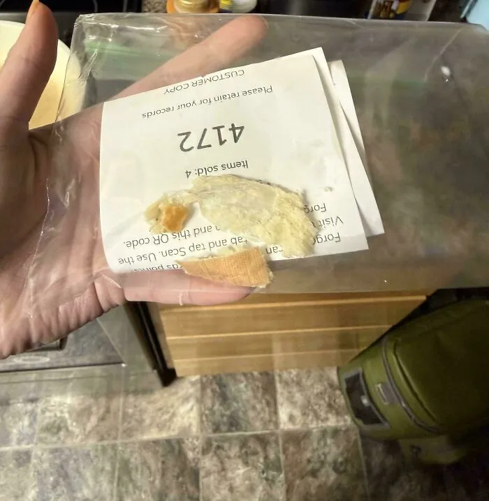 A person holding a receipt with a used bandage stuck to it, a truly bizarre thing to take a photo of.