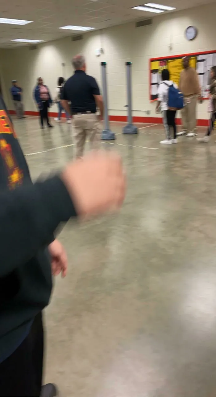 People walking through a room with metal detectors, a scene that makes the American Dream look like a dystopian nightmare.