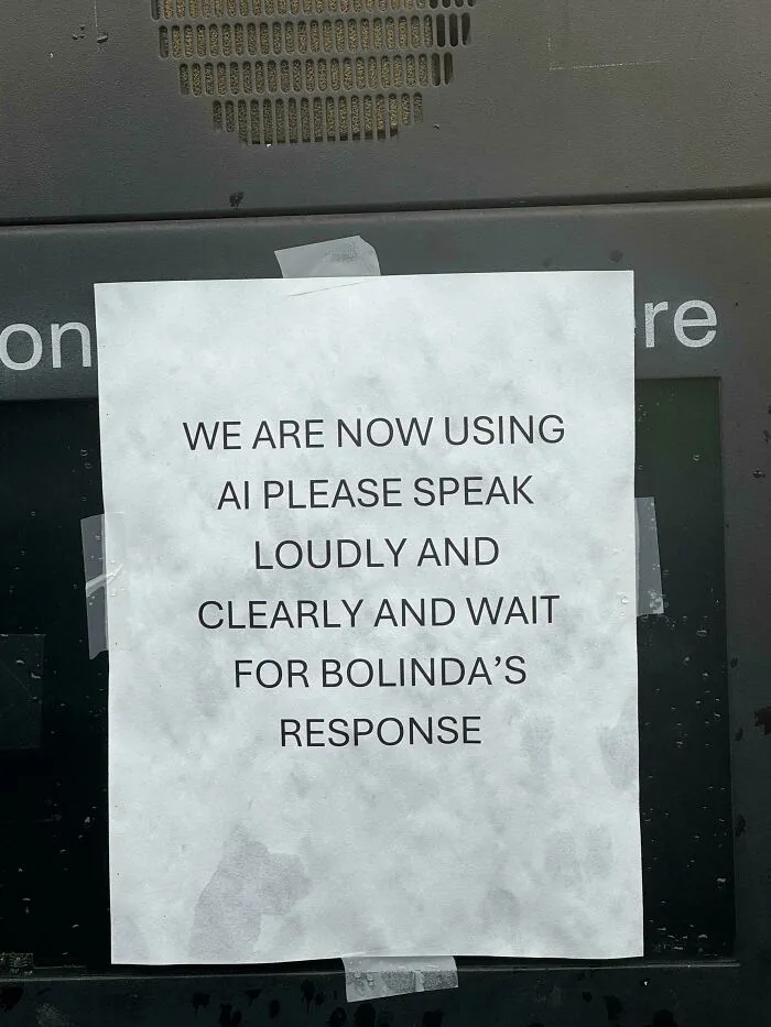 A sign advising customers to speak loudly to an AI, illustrating the dystopian nightmare of technology integration.