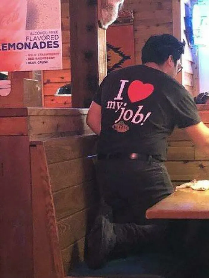 A worker wearing an I love my job shirt, reflecting the dystopian nightmare within the American Dream.