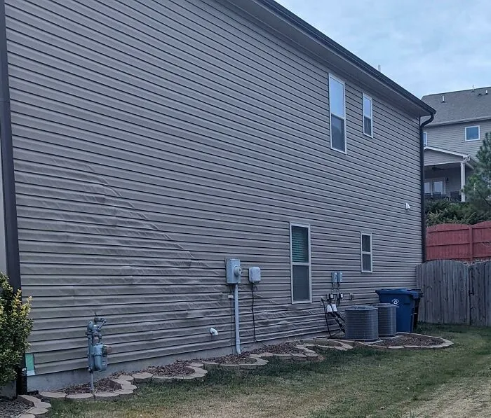 A bizarre thing: the vinyl siding of a house with a wavy, unusual pattern, making it look like it's hallucinating.
