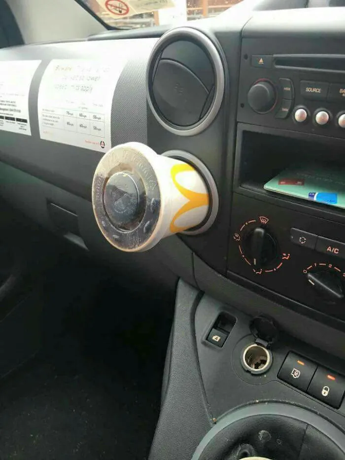 A McDonald's cup used as a car air freshener, an unhinged image of unconventional car accessories.