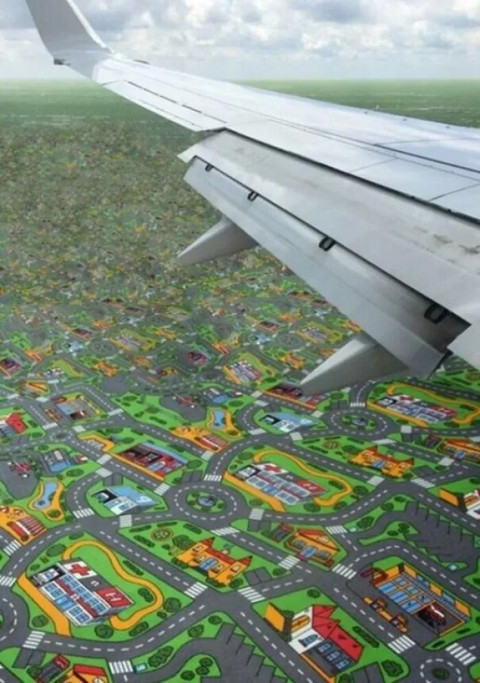 An airplane wing flies over a landscape that looks like a play mat with roads and houses, showcasing unhinged images.
