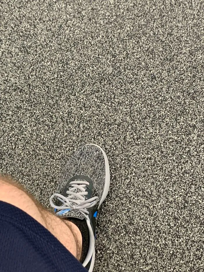 A foot wearing a sneaker that perfectly syncs with the pattern of the speckled floor, an amazing example of something synced just right.