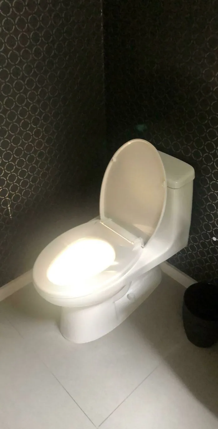 A toilet with a bright light synced perfectly on its seat and lid, creating an amazing glowing effect.