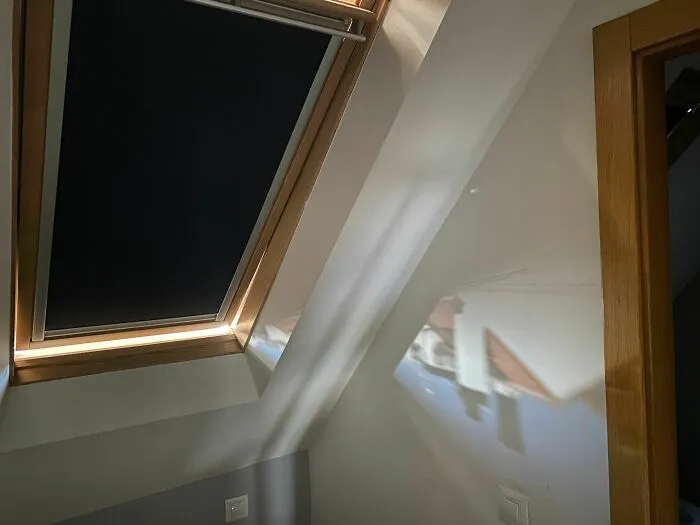 Sunlight shining through a skylight, projecting a perfect image of a house roof on the wall, showing something synced just right.