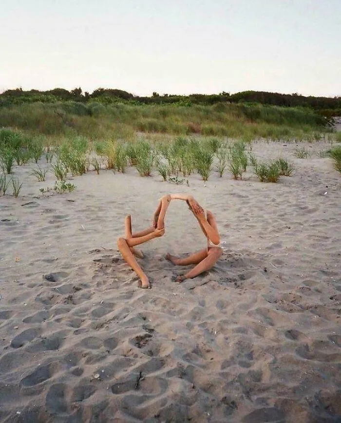 Two people intertwined on a sandy beach, their limbs creating an unhinged and abstract image.