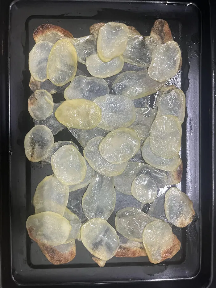 Extremely thin and translucent sliced potatoes laid out on a baking tray, showing questionable food combos.