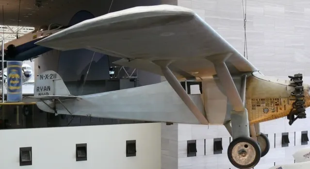 A historic light gray plane, the Spirit of St. Louis, hangs from a museum ceiling, an iconic piece of General Knowledge.