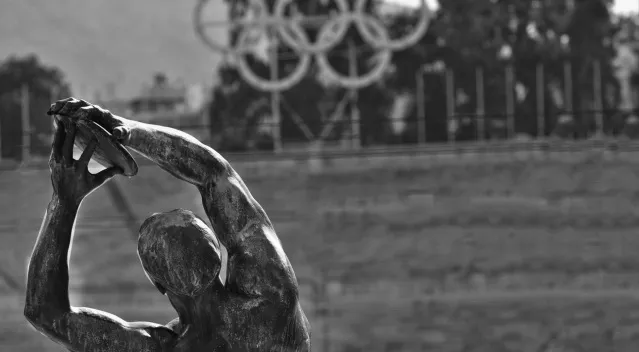 A grayscale image of a discus thrower statue with Olympic rings in the blurry background. Basic General Knowledge Quiz.