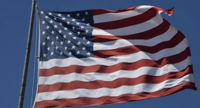 US flag waving against a clear blue sky, evoking thoughts of general knowledge quizzes.