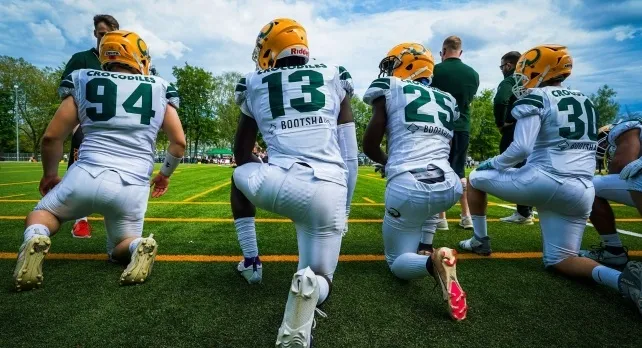 American football players in white and green uniforms kneeling on a field. This image relates to general knowledge quiz.