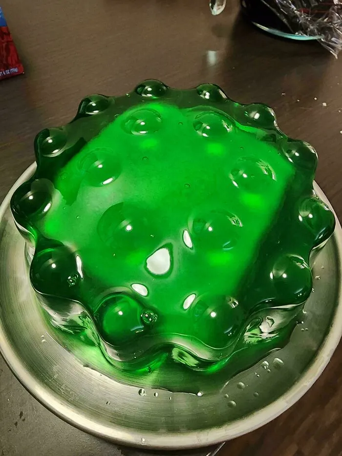 A bizarre molded green gelatin dish served on a silver plate as a questionable food combo.