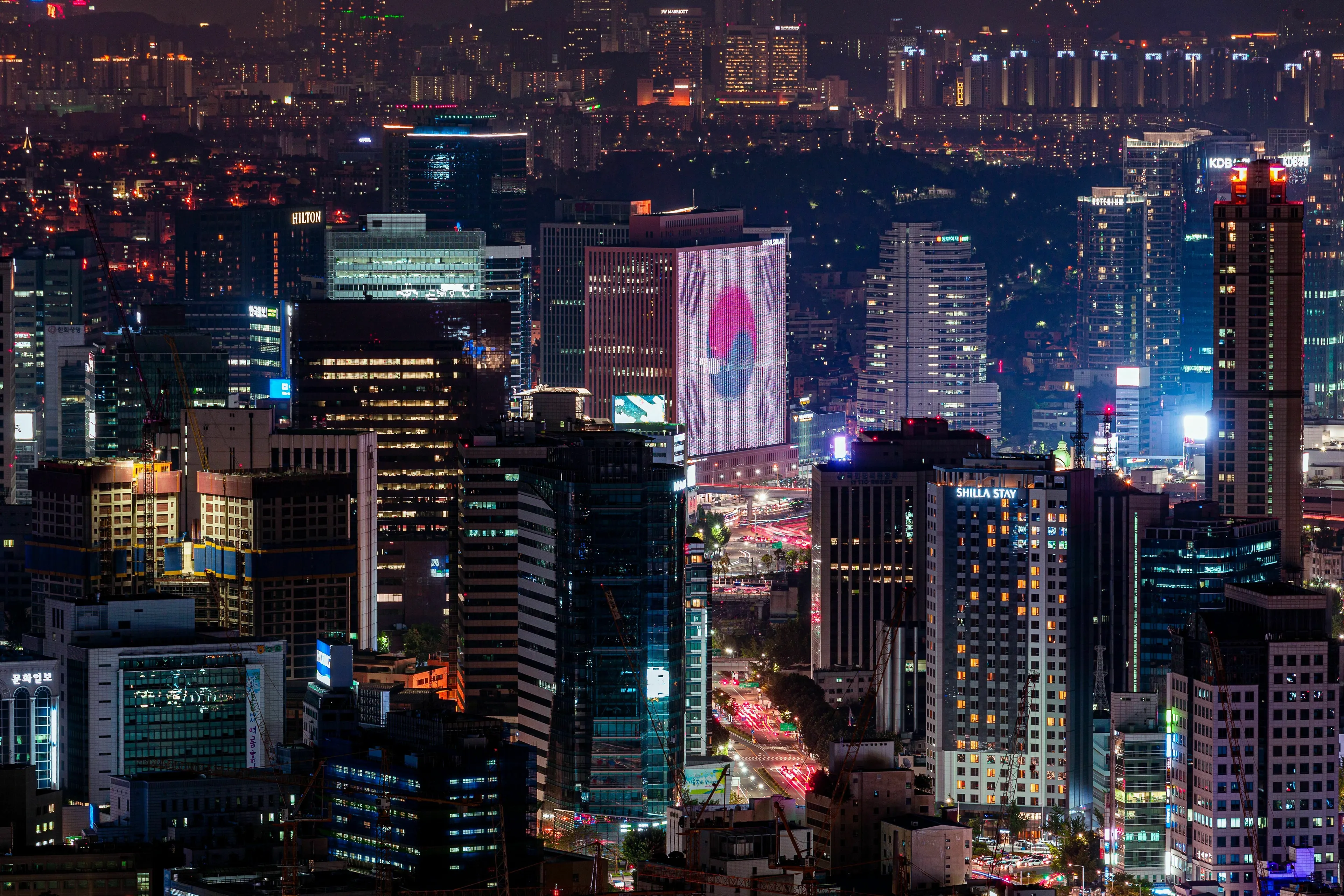 The capital of South Korea, Seoul, shines brightly at night, with towering skyscrapers illuminating the city.