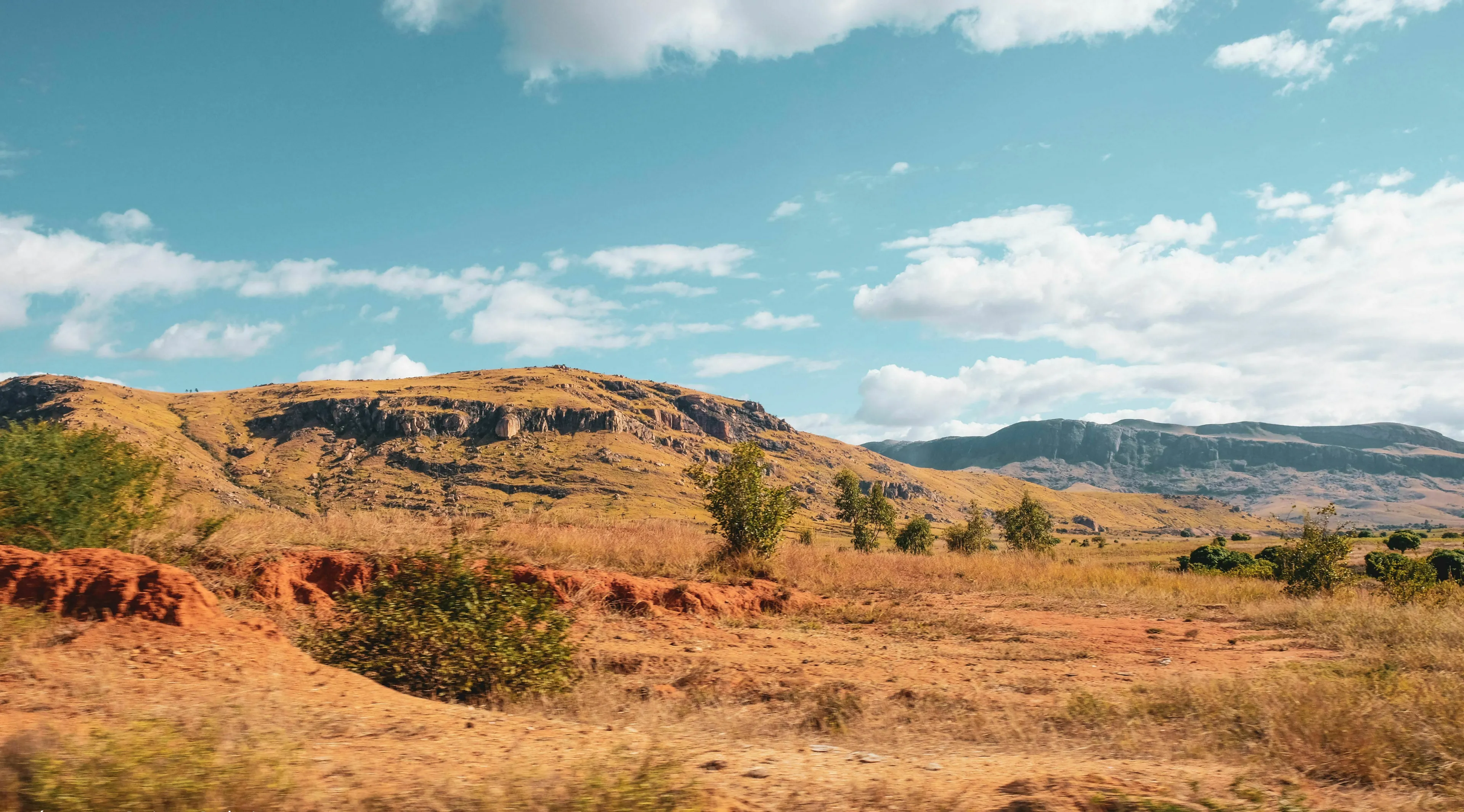 Madagascar landscape with dry, rocky hills under a partly cloudy sky, showing its unique geography.
