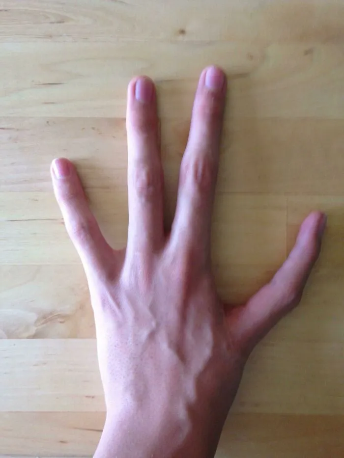 Hand displaying rare six fingers on wooden surface