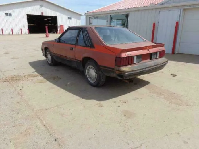 Old red car parked outside a barn evoking nostalgic Gen X childhood vibes