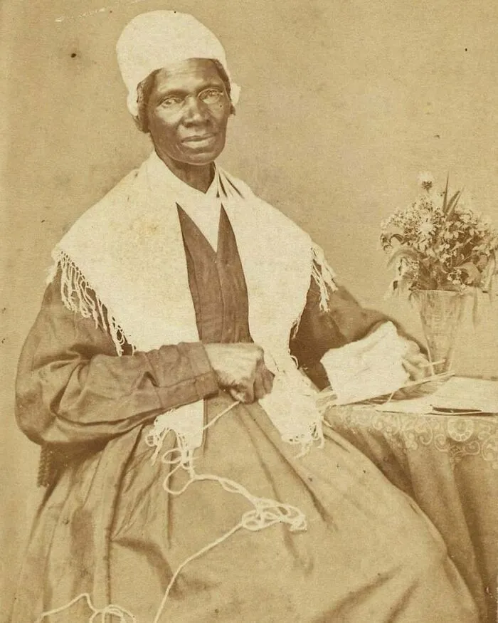 A sepia-toned portrait of a seated Sojourner Truth, an influential figure among Women In History, holding yarn.