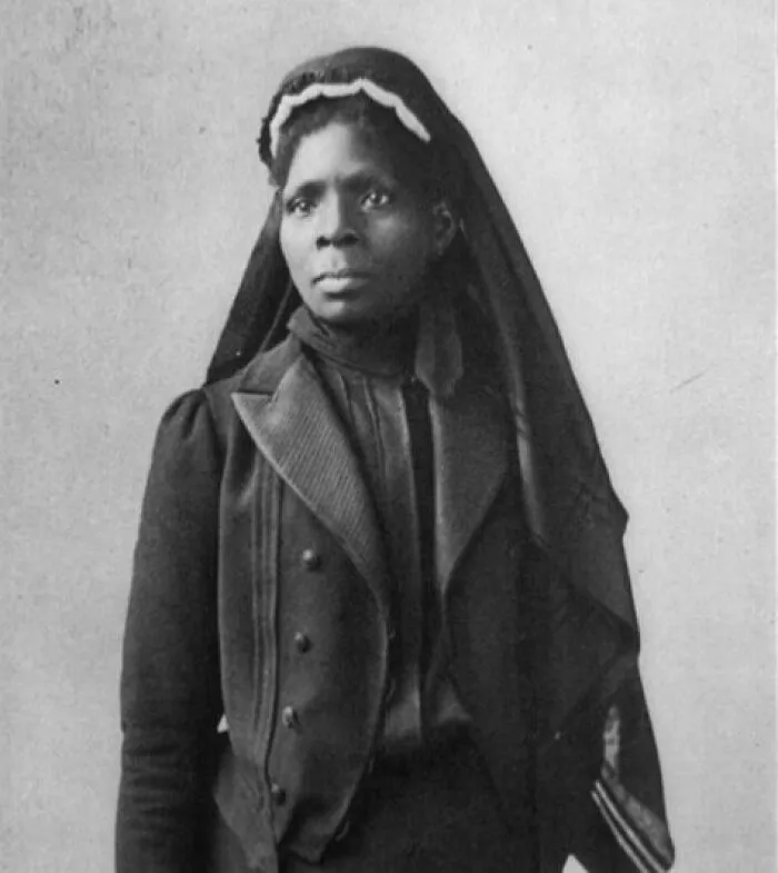 A portrait of a Black woman, a Woman-In-History, wearing a dark dress and head covering.