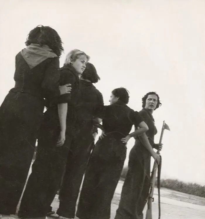 Women-In-History in dark clothes, with one holding a rifle, looking into the distance.