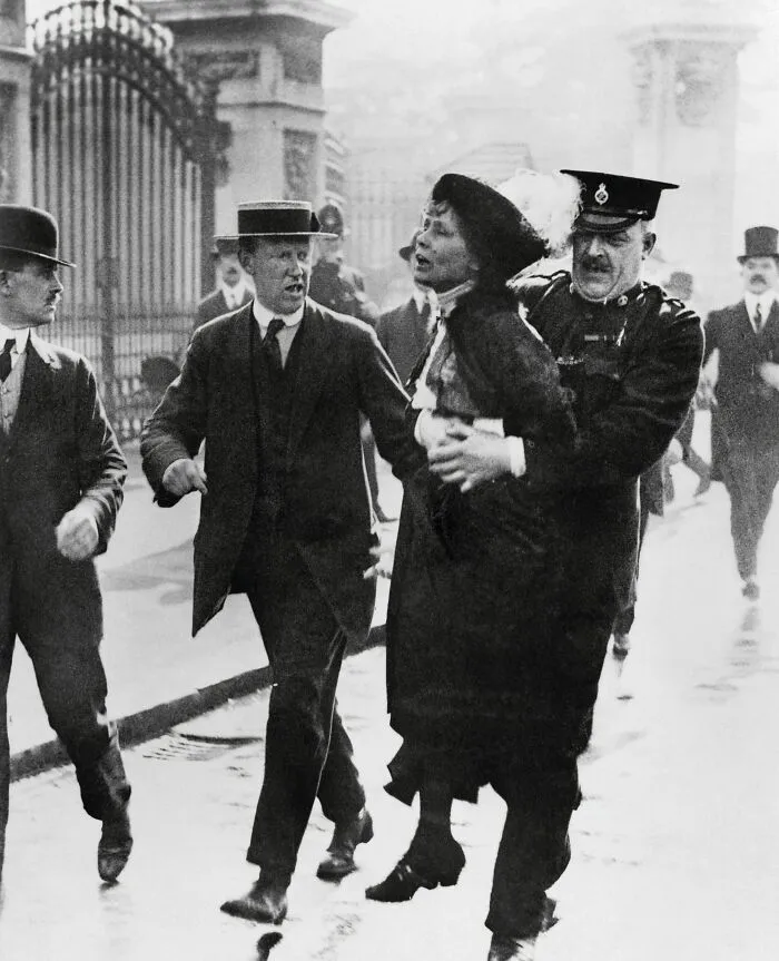 Emmeline Pankhurst, a powerful woman in history, being arrested by a policeman during a protest.