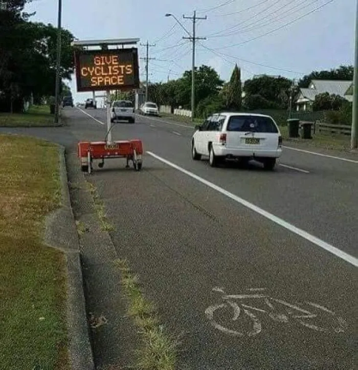 Road sign telling drivers to give cyclists space but blocking the bike lane