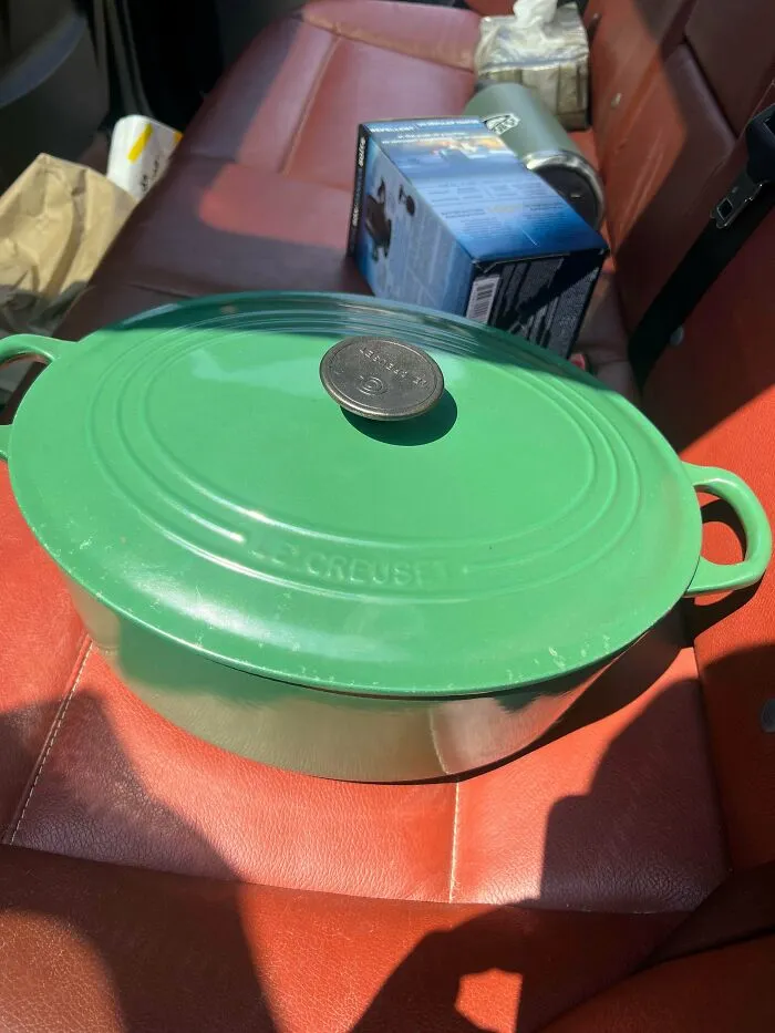A green Le Creuset Dutch oven on a car seat, a lucky discovery among thrift store finds.