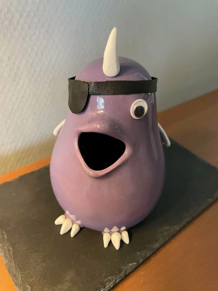 A cute purple ceramic creature with an eyepatch, representing whimsical thrift store finds.
