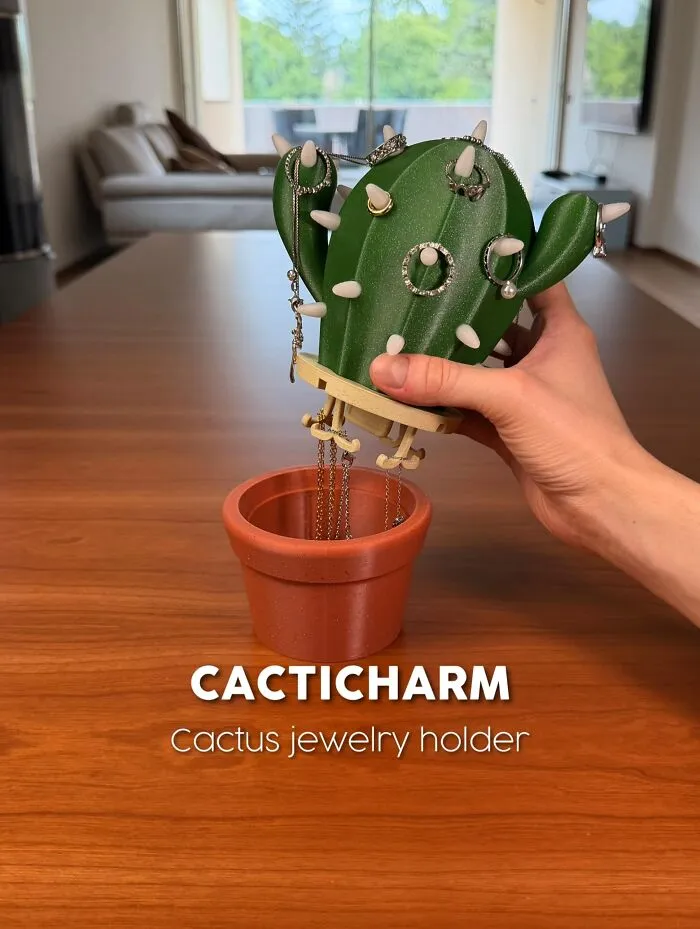 3D printed cactus jewelry holder with rings in a terracotta pot on wooden table
