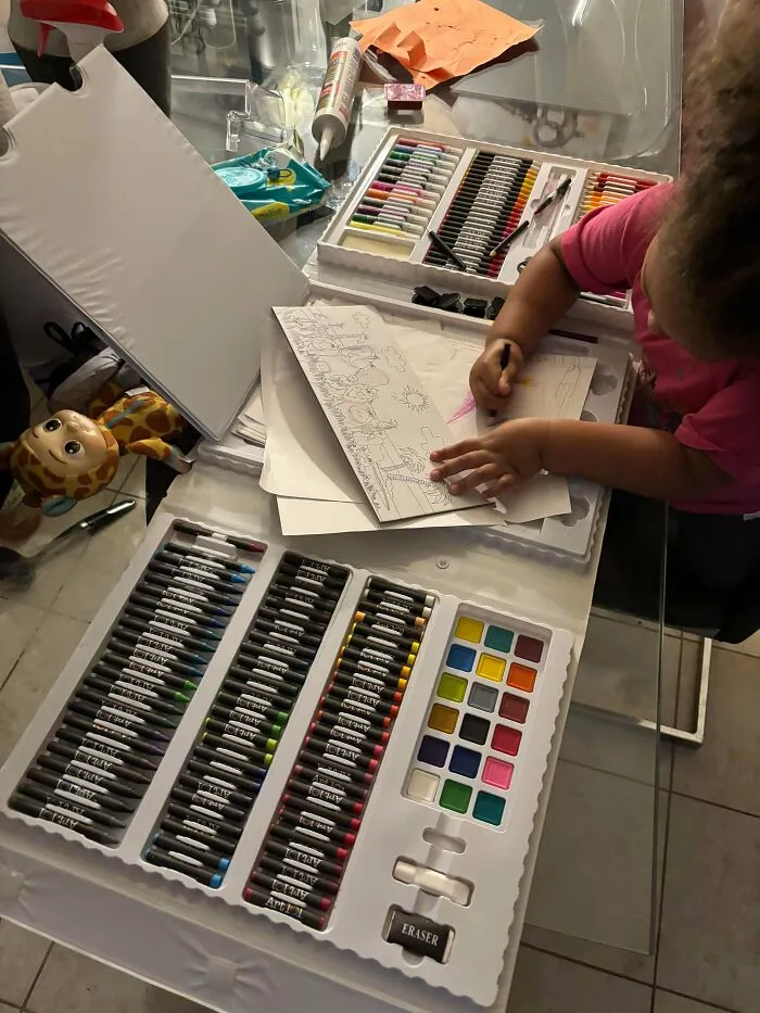 A young child coloring with a large new art set, showing one of many great thrift store finds